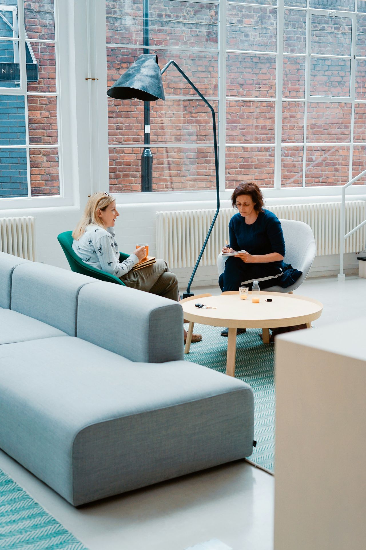 two woman sits on sofa chairs inside house and talk by spectrautomie.be